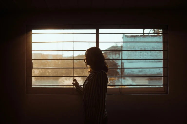 alone girl with window image on article 'Coping With Divorced Parents: What Every Adult Child Needs to Hear'