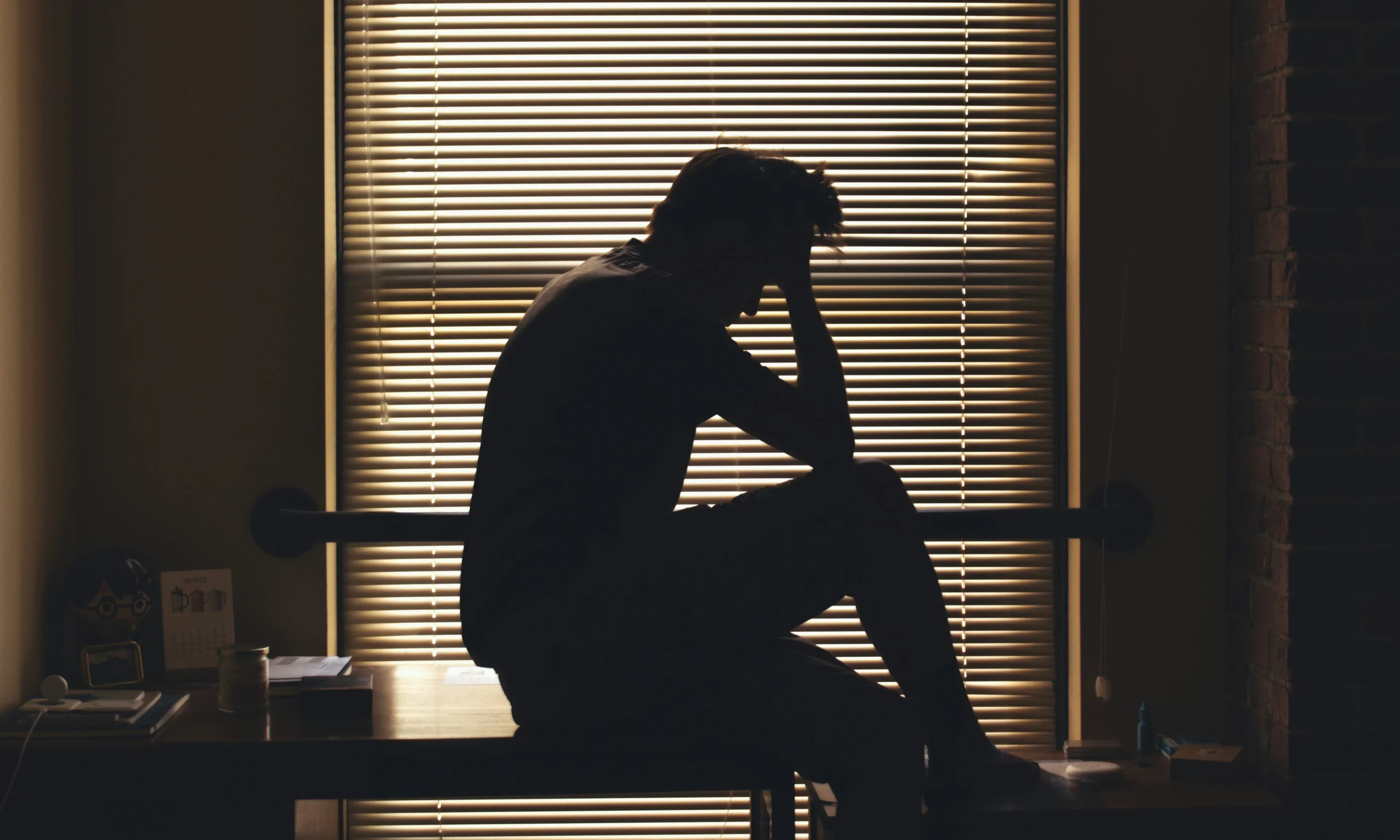 Coping with High-Functioning Anxiety - A Daily Struggle 1 a sad or depress man on table in office mage on article Discover what it's like living with high-functioning anxiety. Learn its signs, real-life experiences, and strategies to manage anxiety while staying productive.